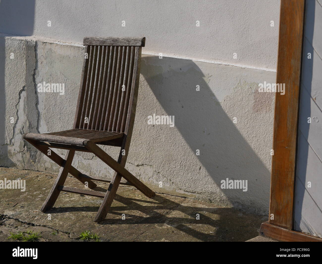 Einsame Holzstuhl mit Schatten an Wand Stockfoto