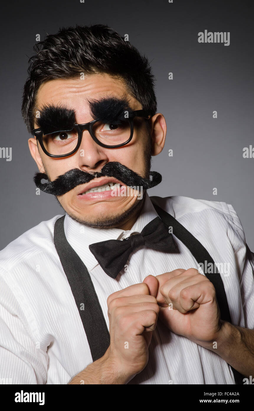 Junger Mann mit falschen Schnurrbart isoliert auf grau Stockfoto