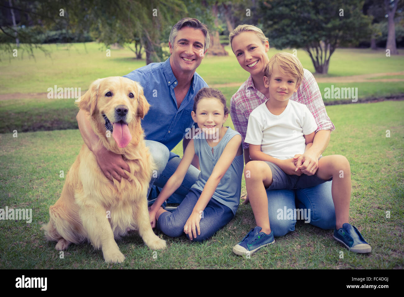 Glückliche Familie lächelt in die Kamera mit ihrem Hund Stockfoto