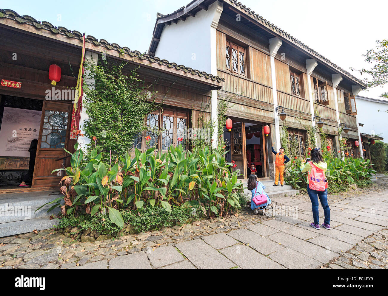 Besucher fotografieren außerhalb ein erhaltenes Haus, das jetzt ein Geschäft ist. XiXi National Wetland Park in der Nähe von Hangzhou, China Stockfoto