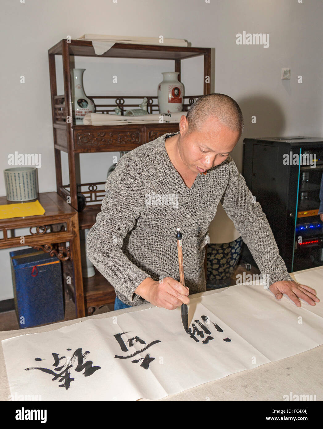 Kalligraphen schreiben chinesische Symbole auf Schriftrolle Zhen Qi Hui Art Center in Hangzhou, China, größte private Museum in China Stockfoto