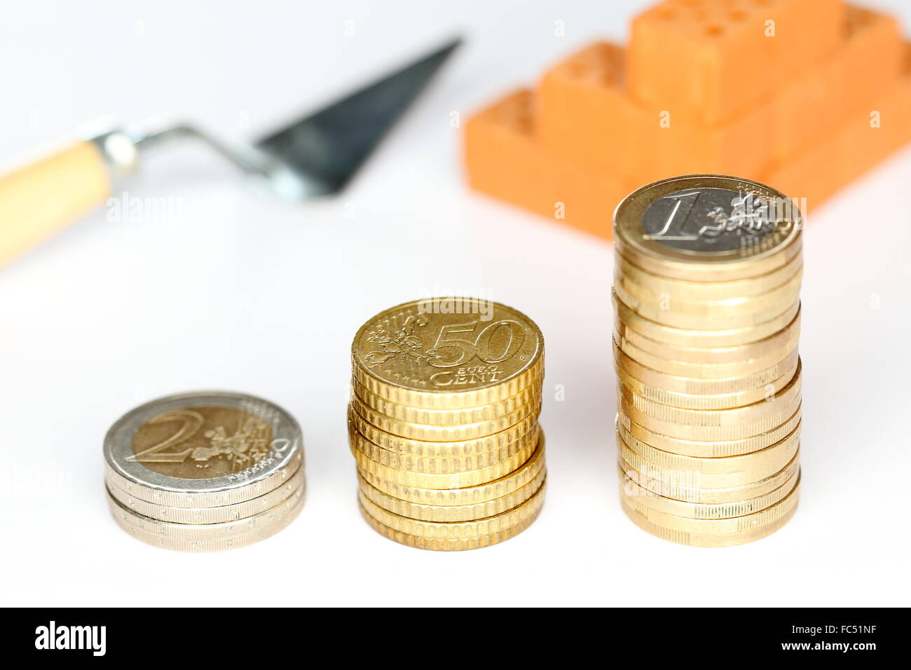 Geld Münzen mit Ziegeln und Werkzeug Stockfoto