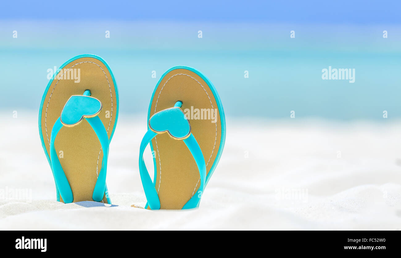 Flip Flops mit Herzen an einem Sandstrand Stockfoto