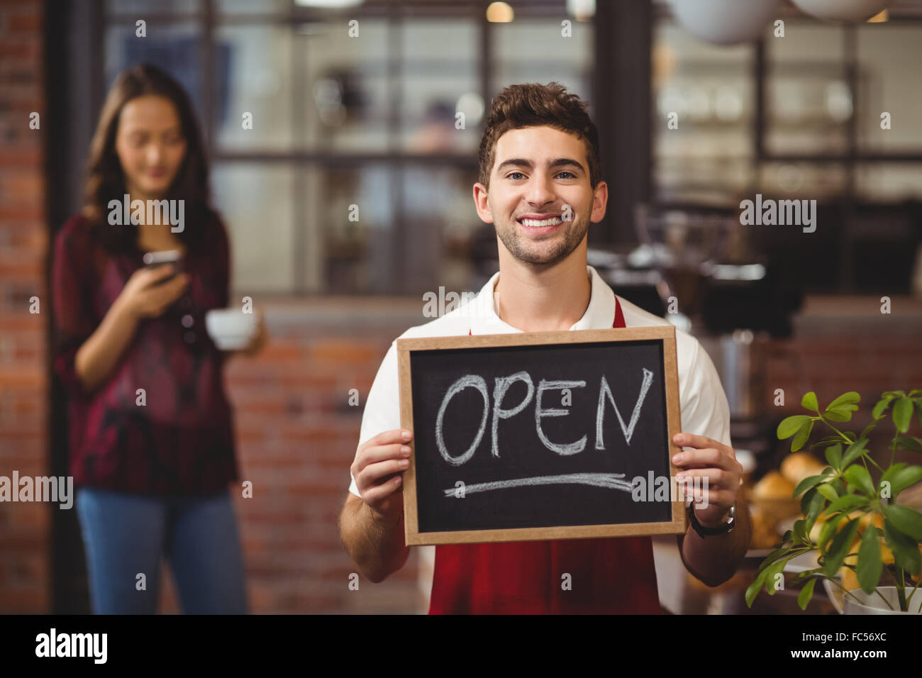 Lächelnden Kellner posiert mit einem Schild "geöffnet" Tafel Stockfoto