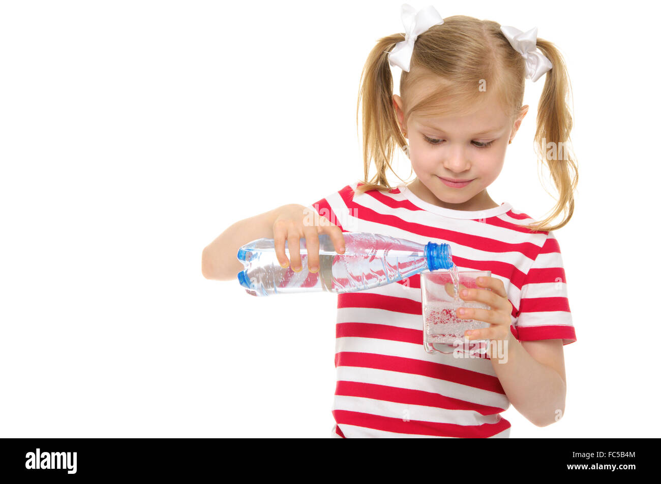 Mädchen gießt Wasser aus der Flasche ins Glas Stockfoto