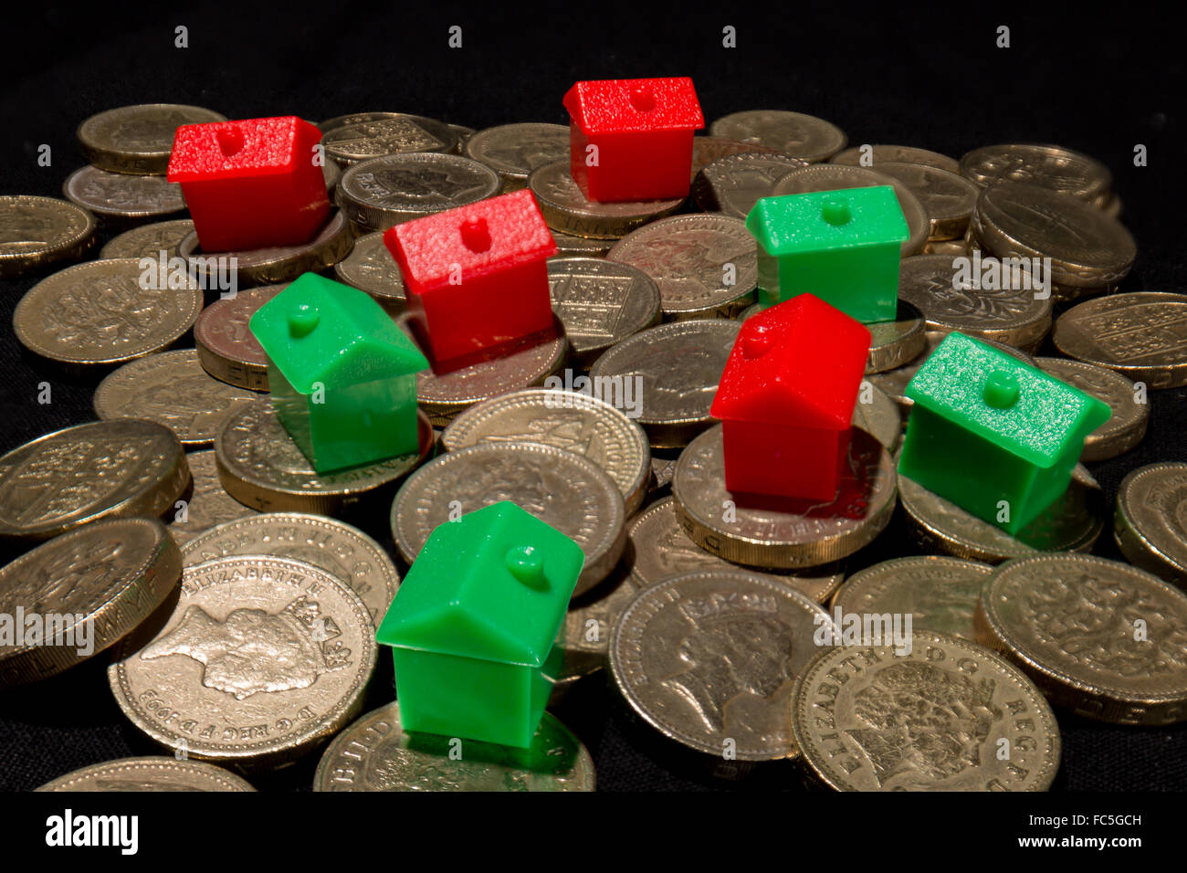 Rote und grüne Häuser auf einen Haufen von britischen Pfund-Münzen Stockfoto