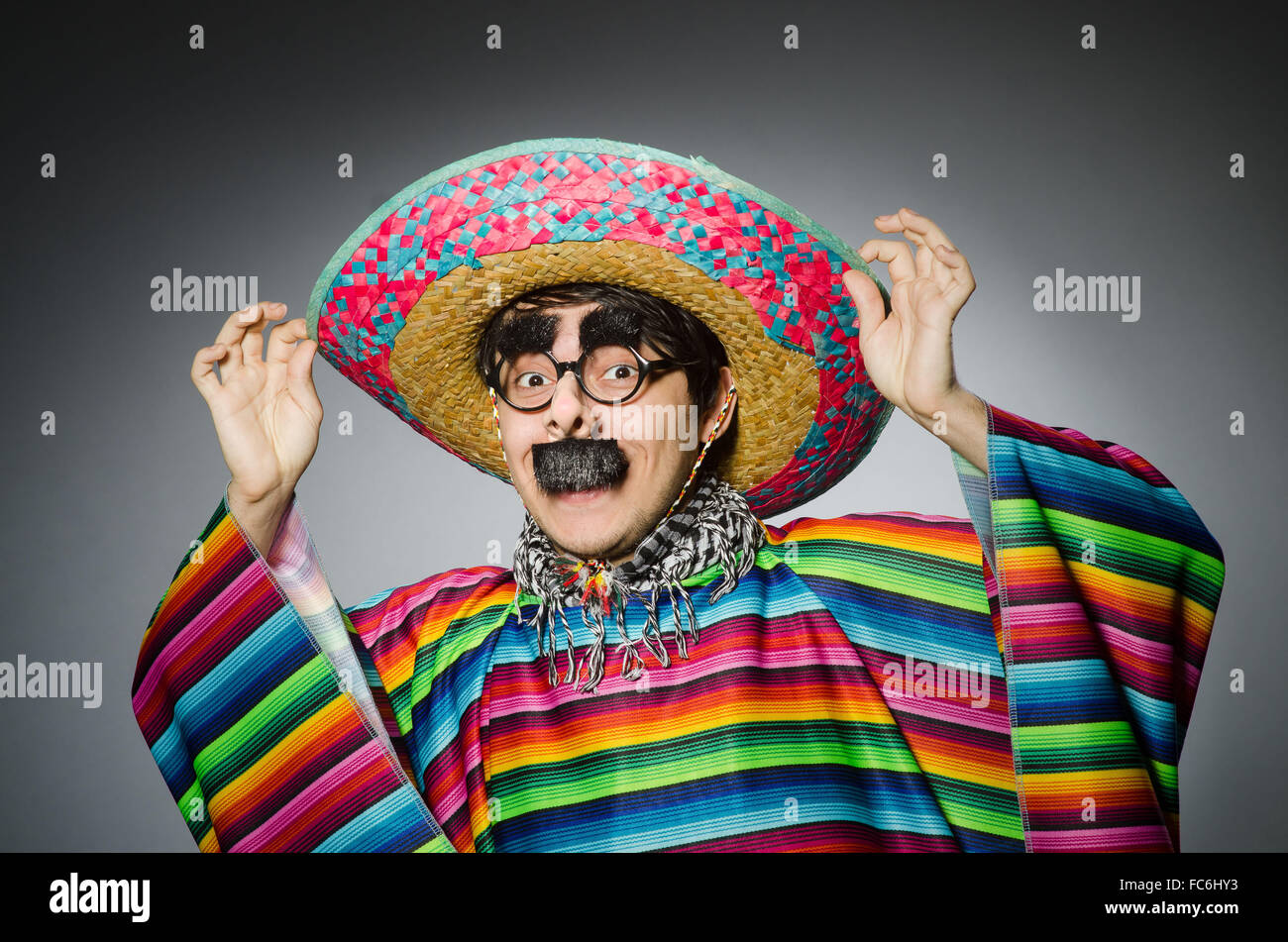 Mann in lebendigen mexikanischen Poncho gegen grau Stockfoto