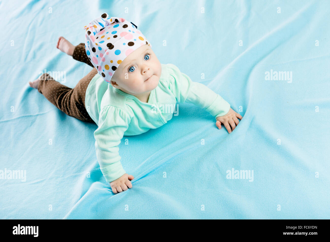 Baby mit Hut auf die blaue Bettdecke krabbeln Stockfoto