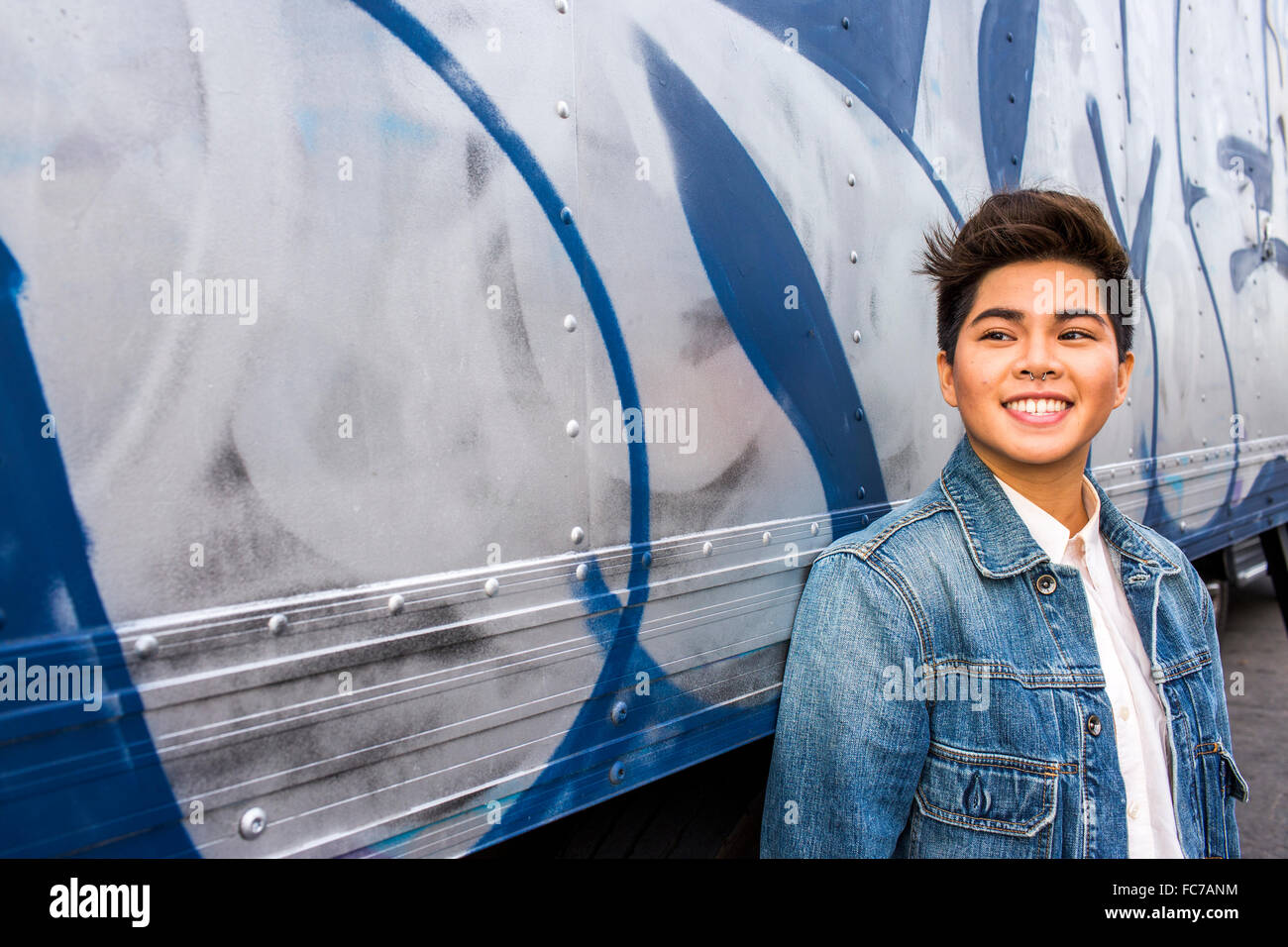 Asiatische Frau lächelnd an Graffitiwand Stockfoto