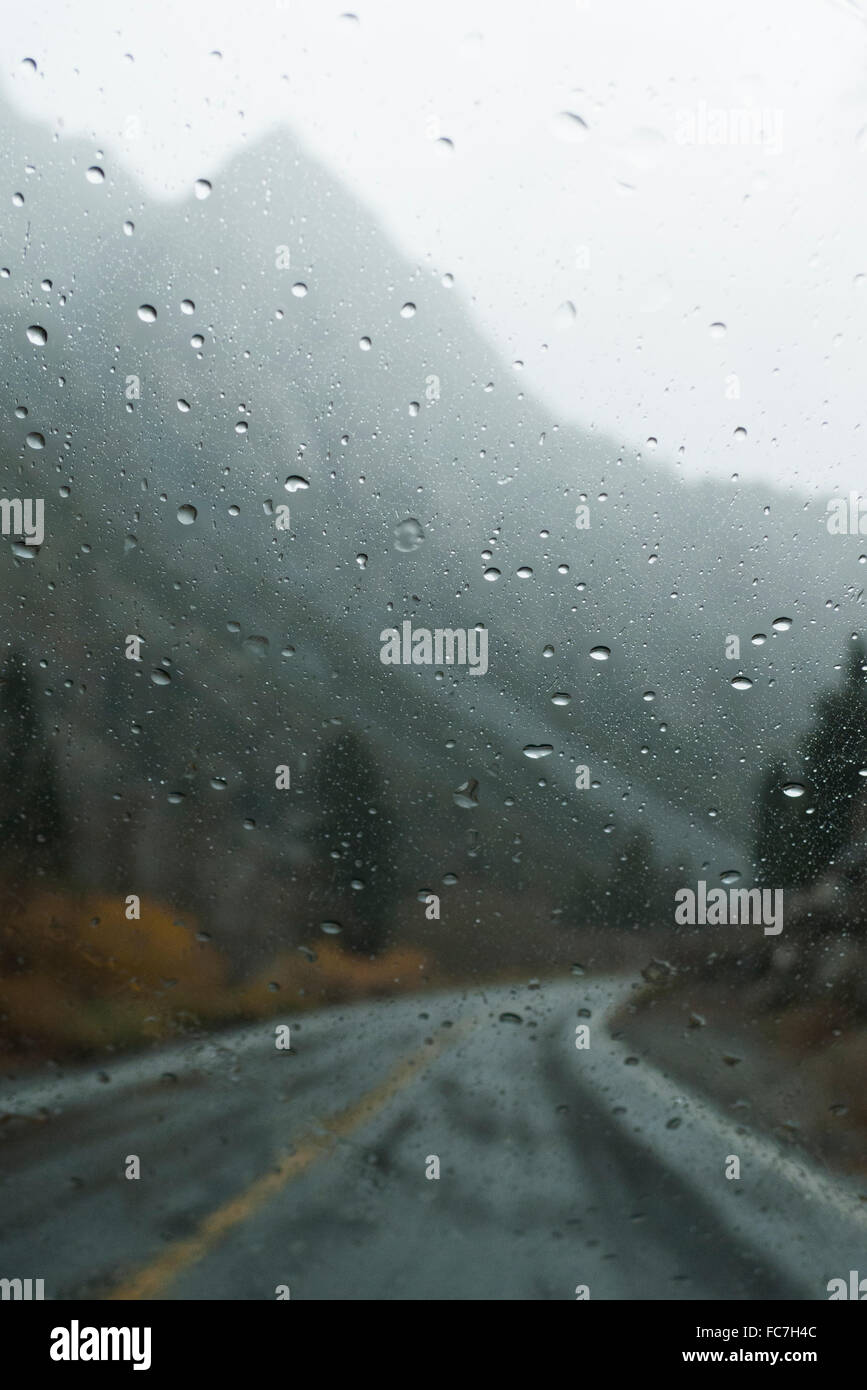 Berge und Landstraße durch nasse Fenster Stockfoto