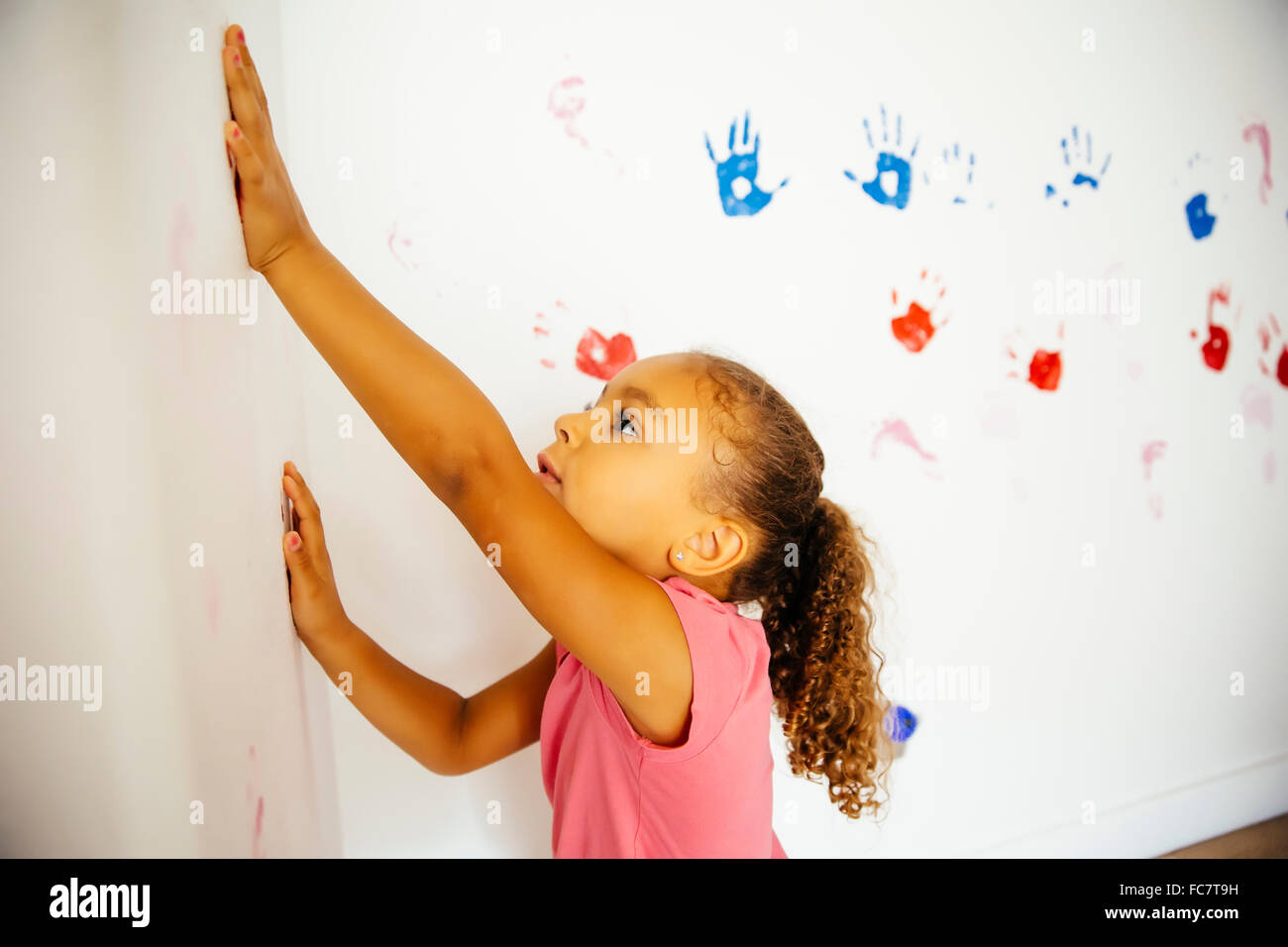 Gemischte Rassen Mädchen die Hand druckt auf Wand Stockfoto