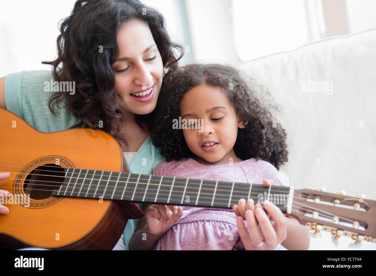 Tochter Mutter Unterricht, Gitarre zu spielen Stockfoto