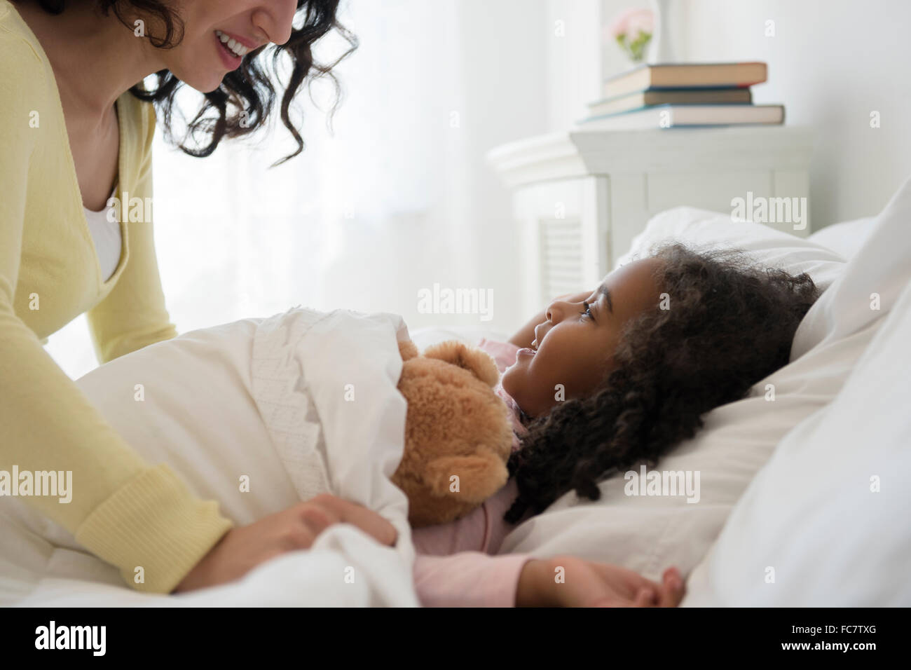 Mutter stopfte Tochter ins Bett Stockfoto