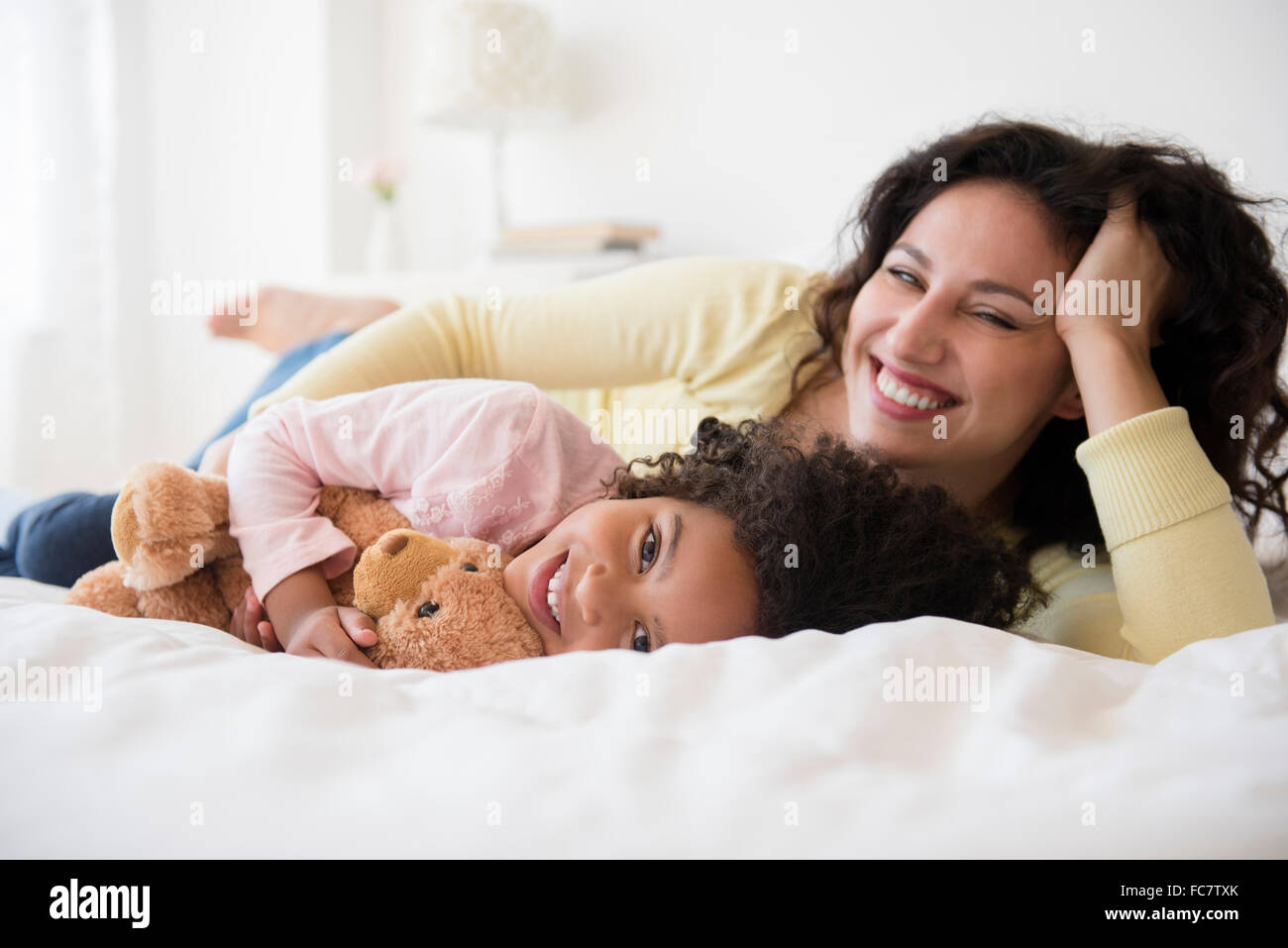 Mutter und Tochter lächelnd auf Bett Stockfoto