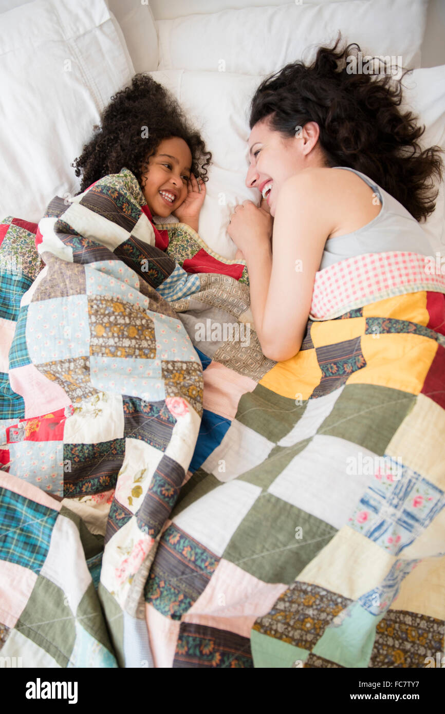 Mutter und Tochter lachend auf Bett Stockfoto