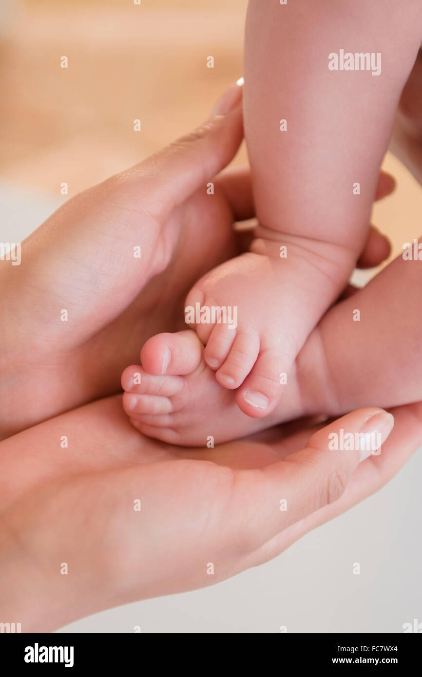 Nahaufnahme der Mutter, die nackten Füße des Babys halten Stockfoto