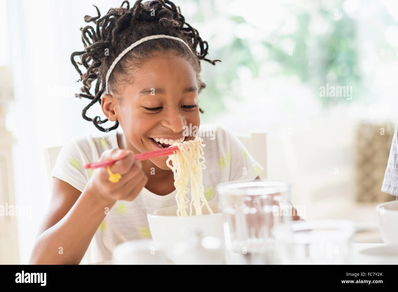 Schwarzes Mädchen essen Nudeln am Tisch Stockfoto