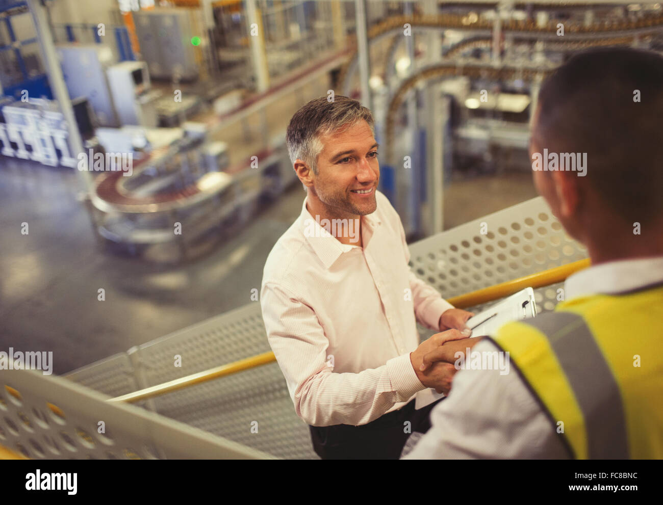Supervisor und Arbeitskraft Handshaking in Fabrik Stockfoto