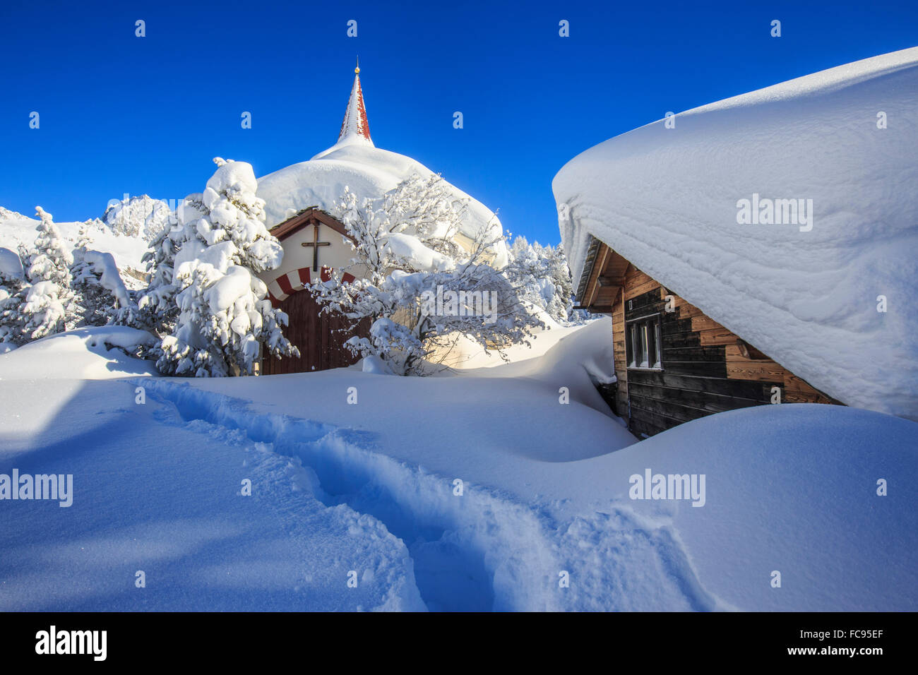 Die kleine Kirche und das Haus unter Wasser durch Schnee nach einem Schneefall in Maloja, Engadin, Graubünden, Schweiz Stockfoto