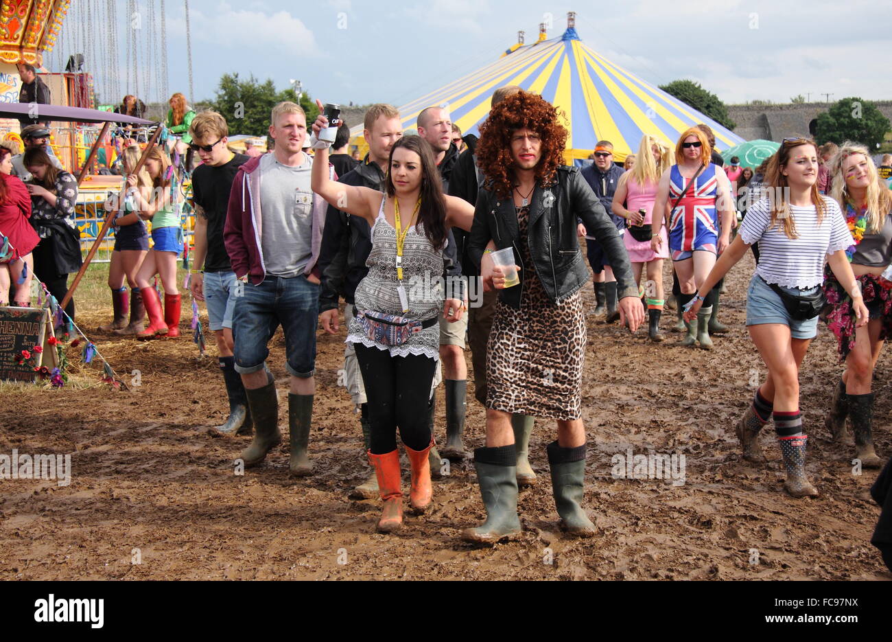 Festivalbesucher umarmen das Jahresthema Kostüm auf dem Festival Y nicht überqueren einen schlammigen Feld nach Regen, Derbyshire UK Stockfoto