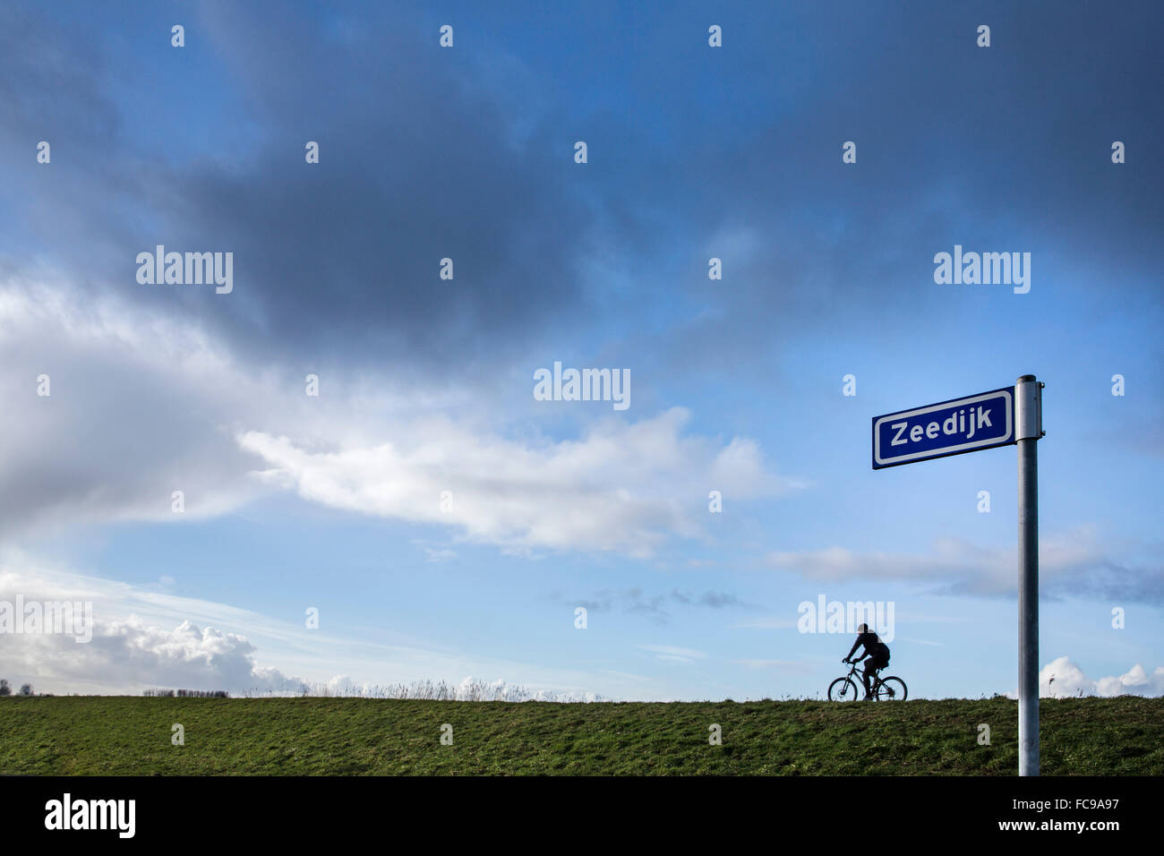 Niederlande, Putten, Arkemheen Polder, Straßenschild mit Namen Landstraße: Deich auf Niederländisch: Zeedijk. Radfahrer am Deich Stockfoto