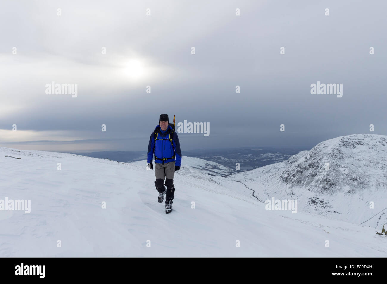 Walker und der Blick über Kirkstone Pass von den oberen Hängen des Caudale Moor in sich verschlechternde Wetter, Lake District von Cumbria Stockfoto