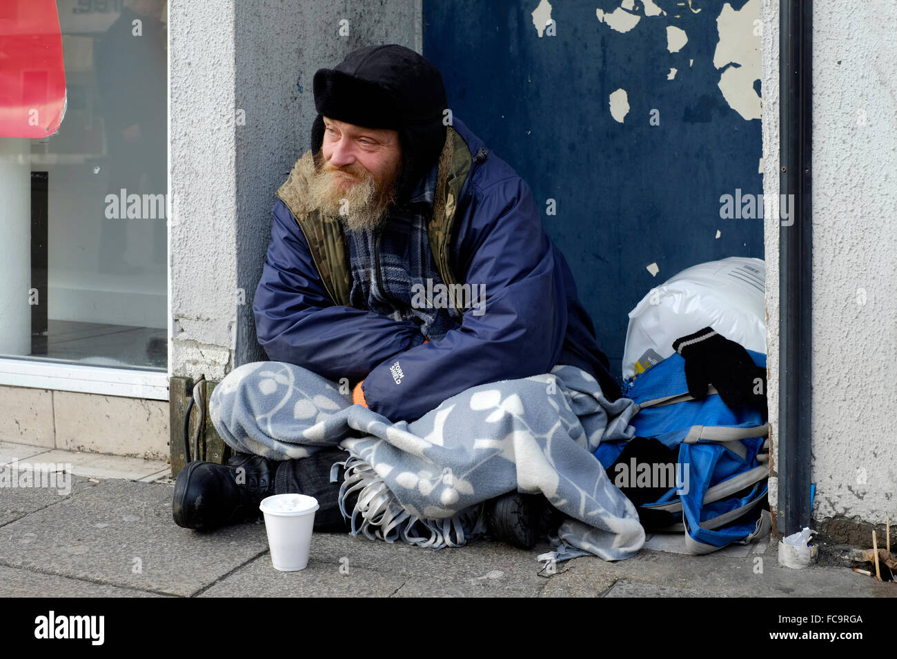 Obdachlosen Mann sitzt in einer Stadt Zentrum Tür England uk Stockfoto