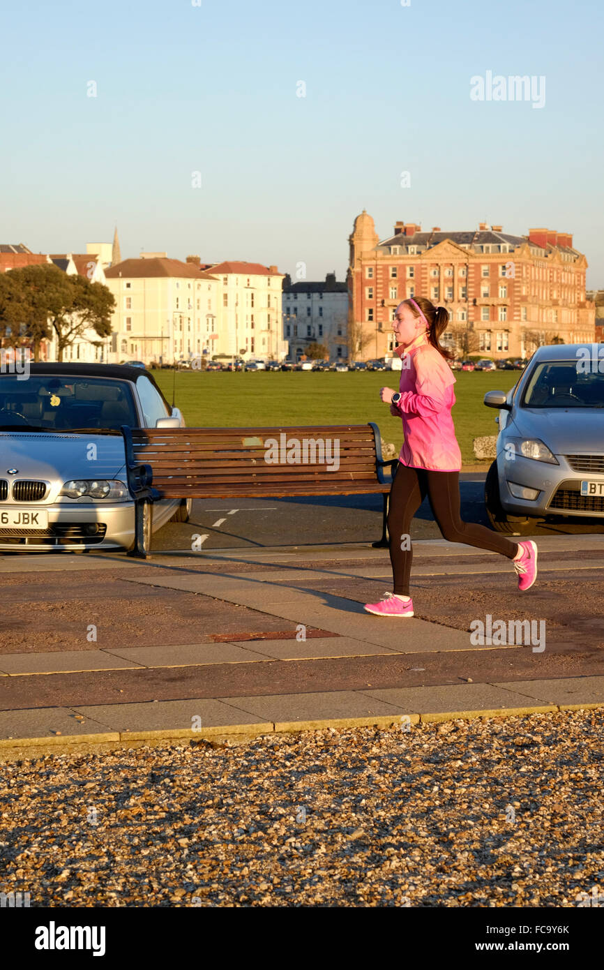junge Frau joggt im goldenen Licht des Sonnenuntergangs an der Strandpromenade von Southsea England uk Stockfoto