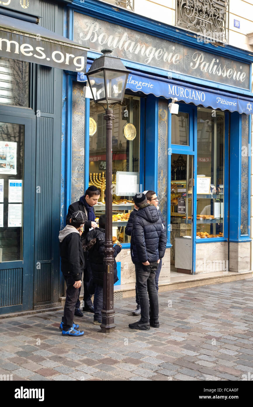 Jüdische Kinder essen Kuchen vor Bäckerei Marciano, Jüdisches Viertel in Marais, Paris, Frankreich. Stockfoto