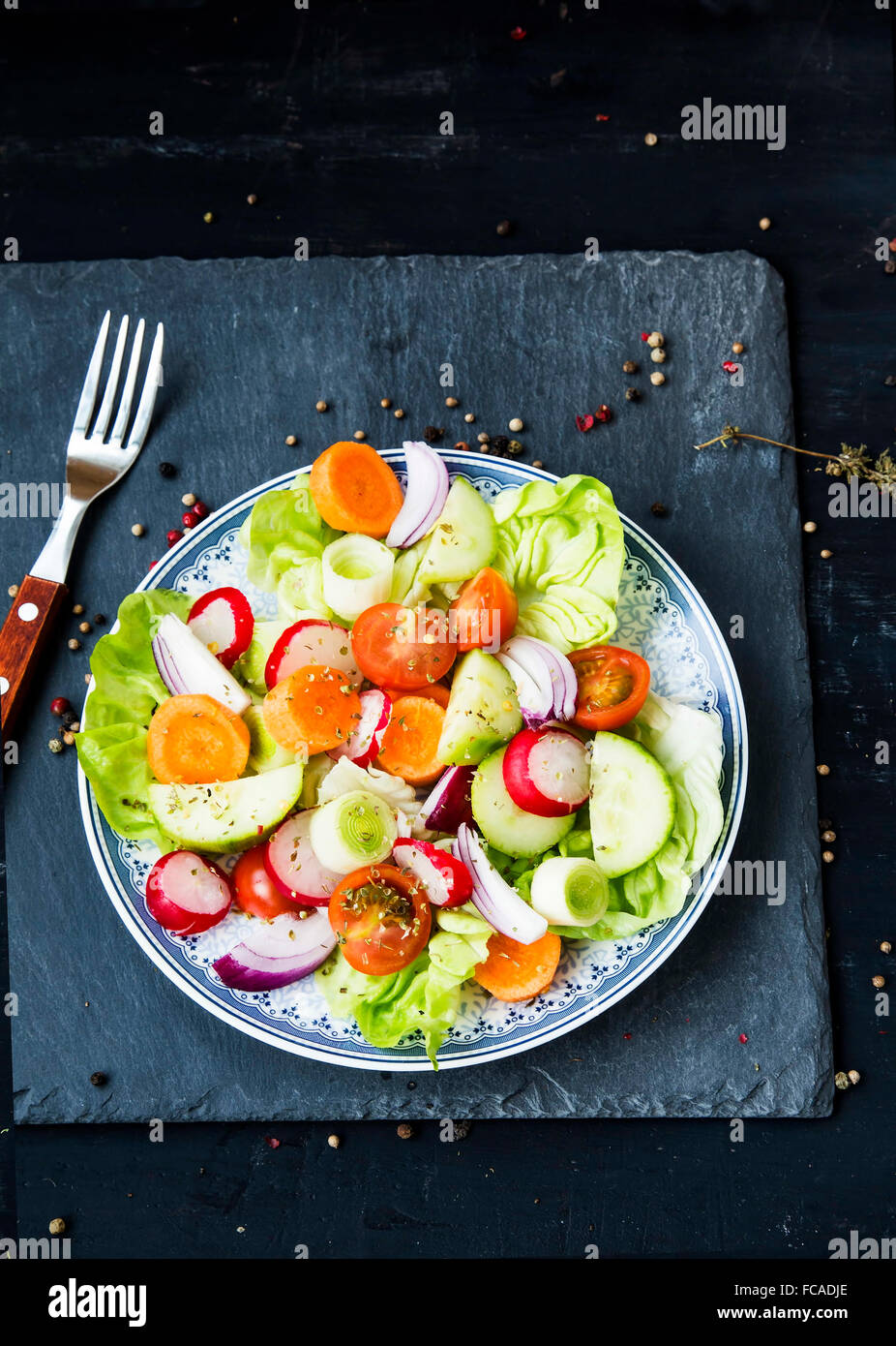 Frisches Gemüse-Salat mit Radieschen, Gurken, Tomaten, Salat, Karotten, Zwiebeln und Gewürzen mischen Stockfoto