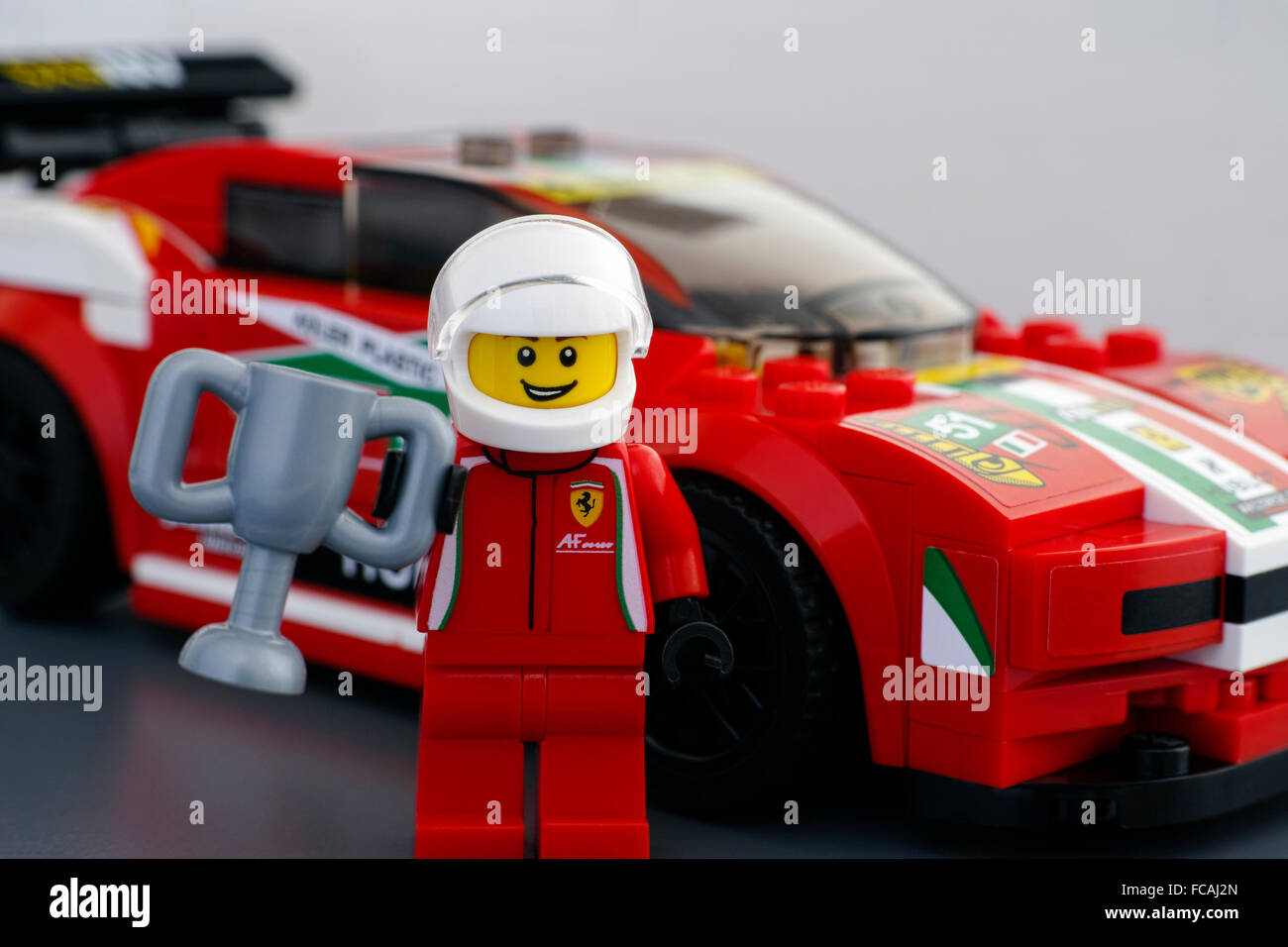LEGO Ferrari Fahrer Minifigur mit Tasse von LEGO Geschwindigkeit Champions und sein Auto Ferrari 458 Italia GT2 auf Hintergrund. Stockfoto