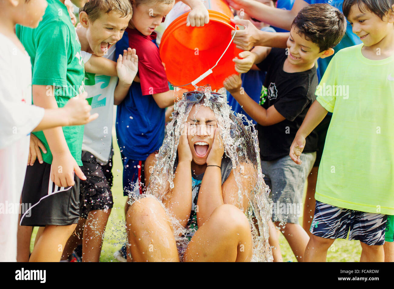 Kinder im Sommercamp in San Diego, Kalifornien, Gießen Sie einen Eimer mit Wasser auf einer von ihnen. Stockfoto