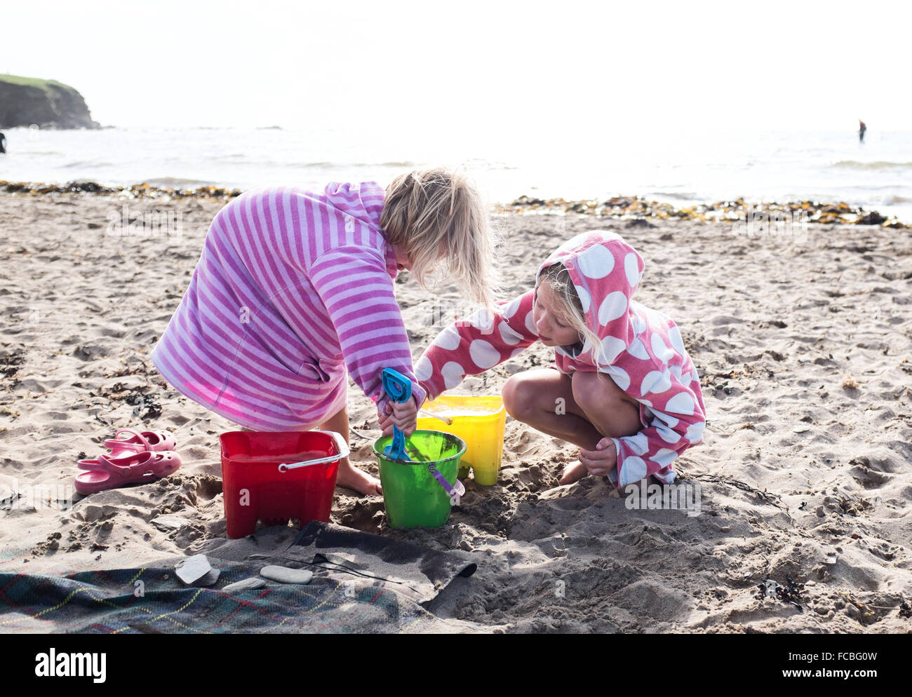 Zwei Mädchen spielen am Strand mit Eimer und Spaten Stockfoto