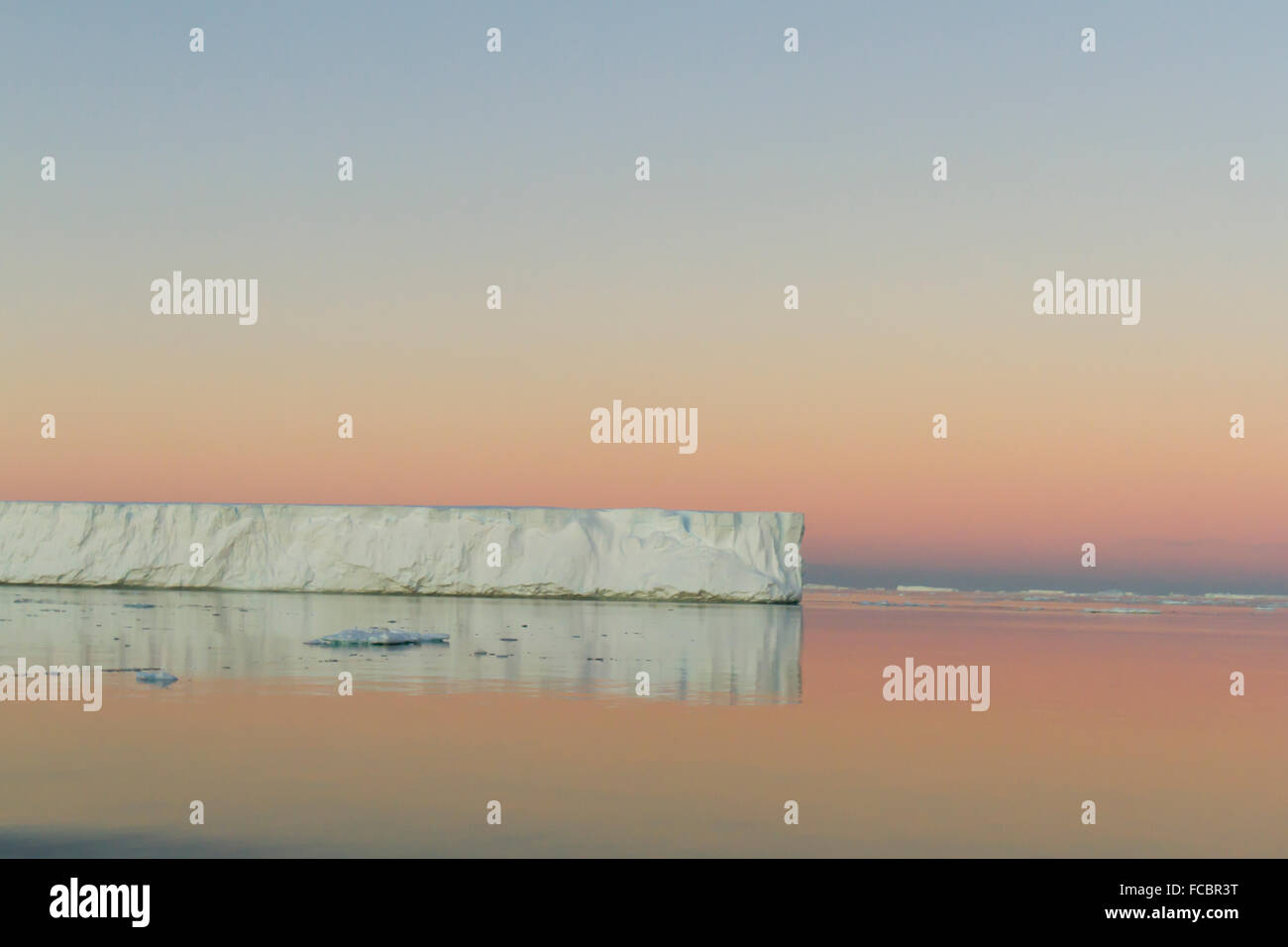 Tabellarischen Eisbergs spiegelt sich in ruhigen Gewässern der Antarktis Sound bei Sonnenuntergang. Stockfoto