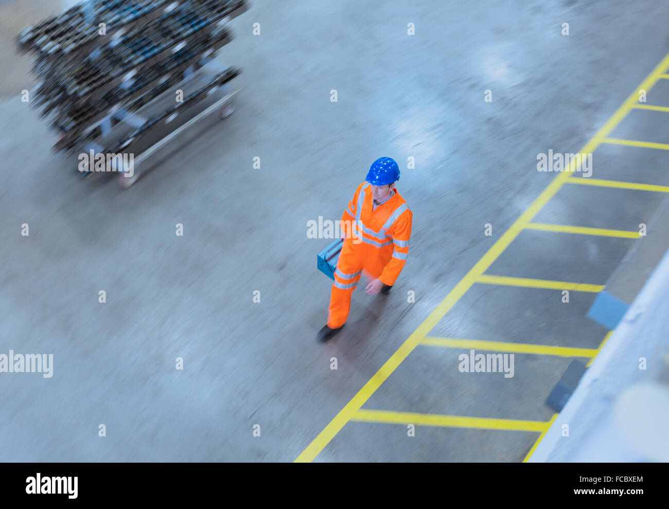 Arbeiter in reflektierende Kleidung, die zu Fuß mit Toolbox in Fabrik Stockfoto