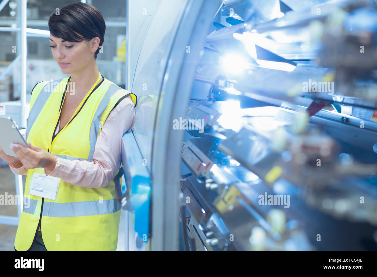 Arbeiter mit digital-Tablette lehnt sich an Maschinen in der Fabrik Stockfoto