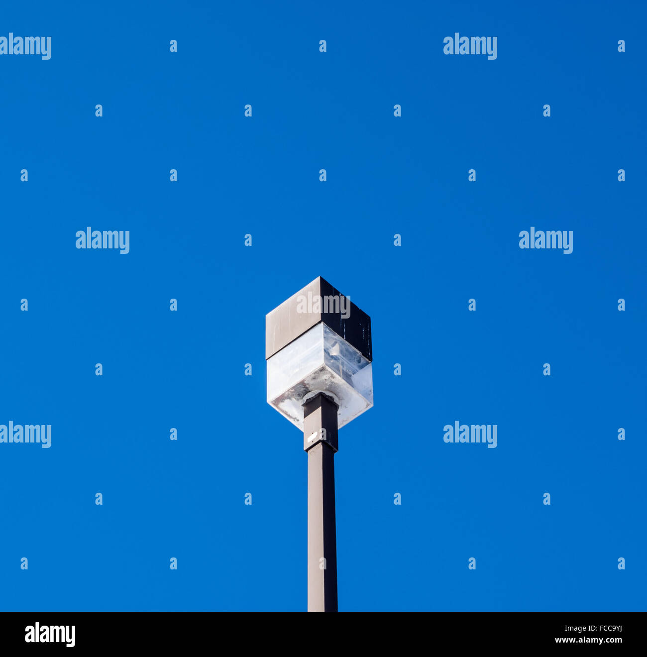 Würfelförmige street lamp von unten auf rechteckigen post anhand klarer, blauer Himmel. Stockfoto