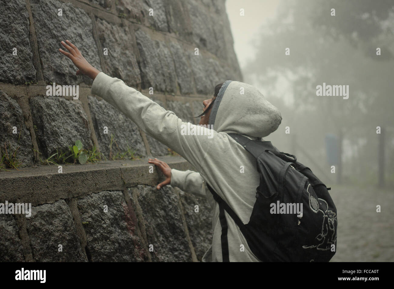 Teenager berühren Steinmauer Stockfoto
