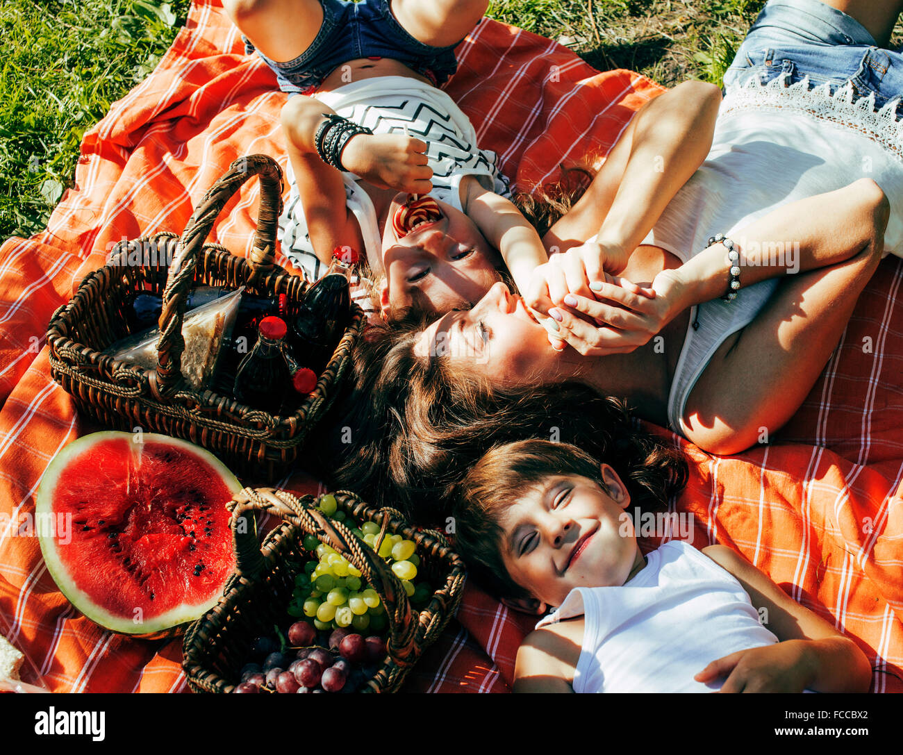 niedliche glückliche Familie Picknick auf grünen Rasen Mutter und Kinder, warmen Sommerferien schließen sich Bruder und Schwester Stockfoto
