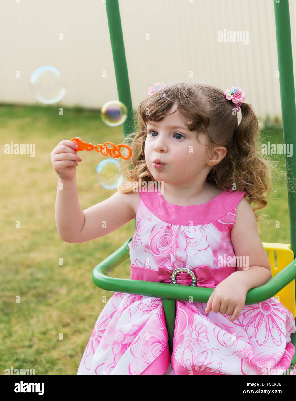 niedliche kleine Mädchen schwingen auf Wippe und das Spiel mit Seifenblasen Stockfoto