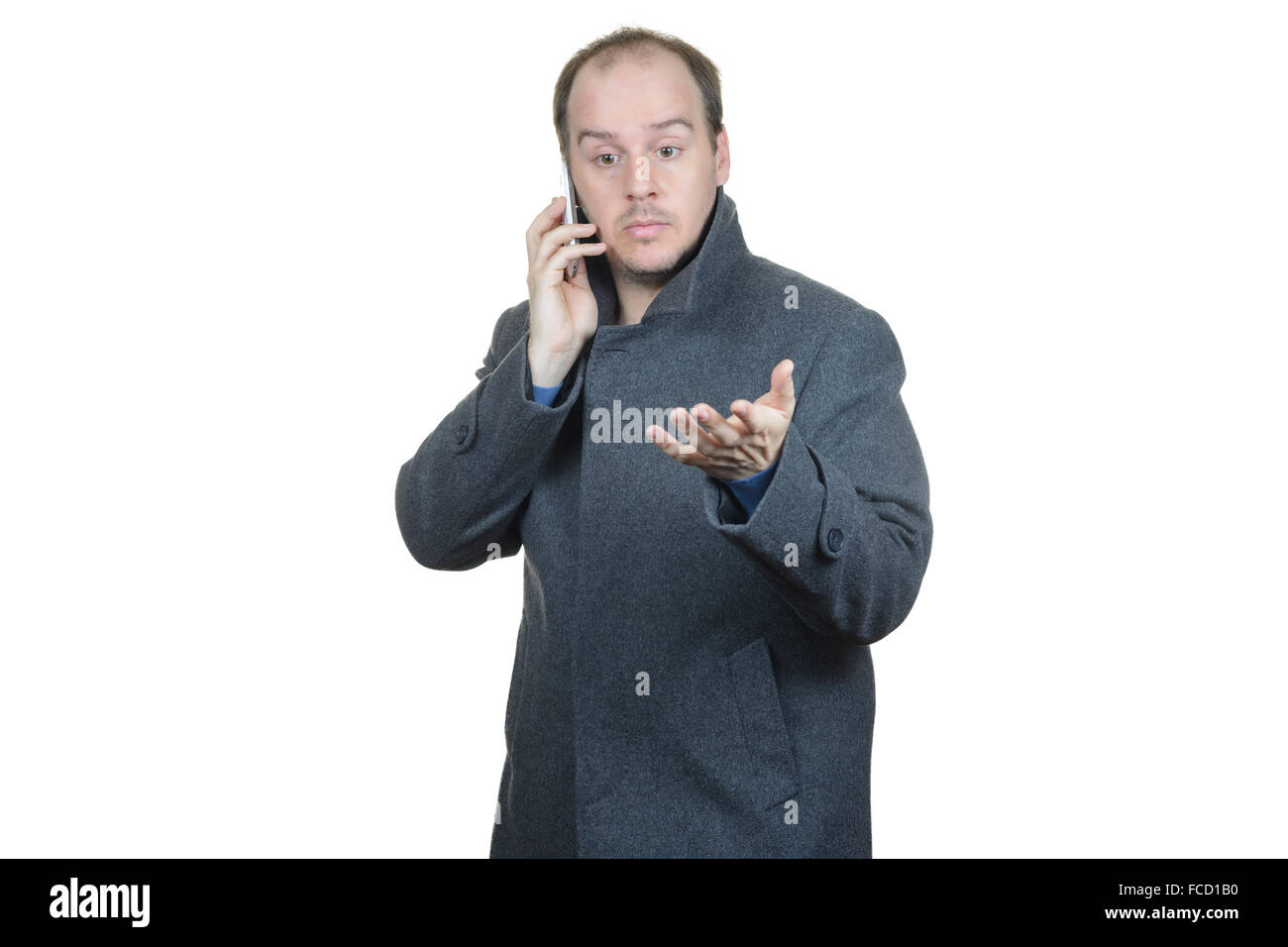 junger Mann dunklen grauen Mantel Telefon gestikulierend im Gespräch Stockfoto
