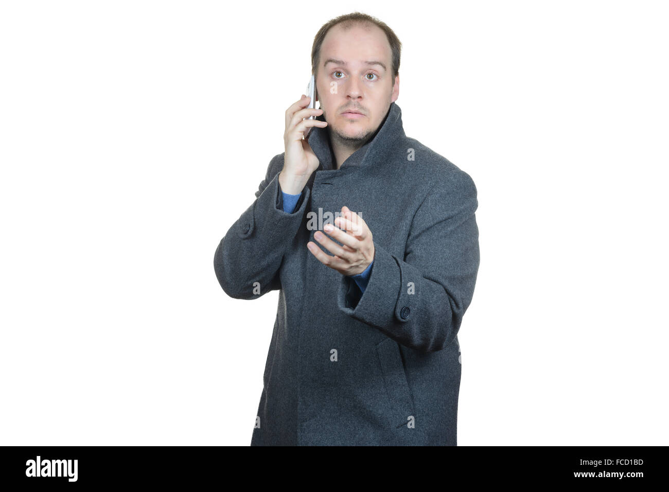 junger Mann dunklen grauen Mantel Telefon gestikulierend im Gespräch Stockfoto