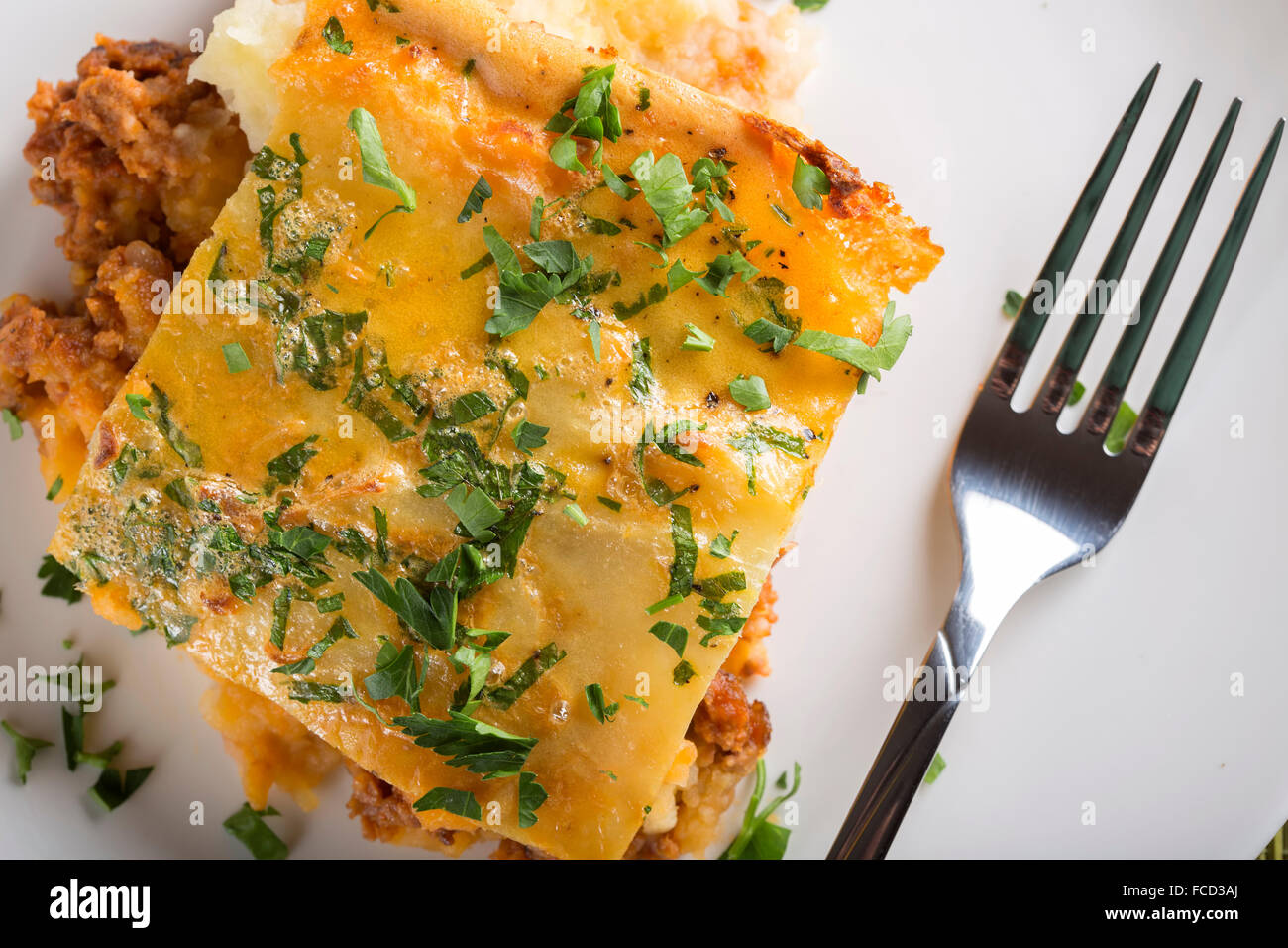 Moussaka mit Hackfleisch, Kartoffeln und Petersilie auf weißen Teller Stockfoto