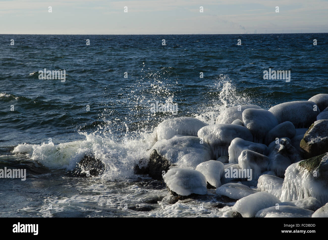 Felsen von einer Küste mit einem tiefblauen Wasser bedeckt Plätschern der Wellen am Eis Stockfoto