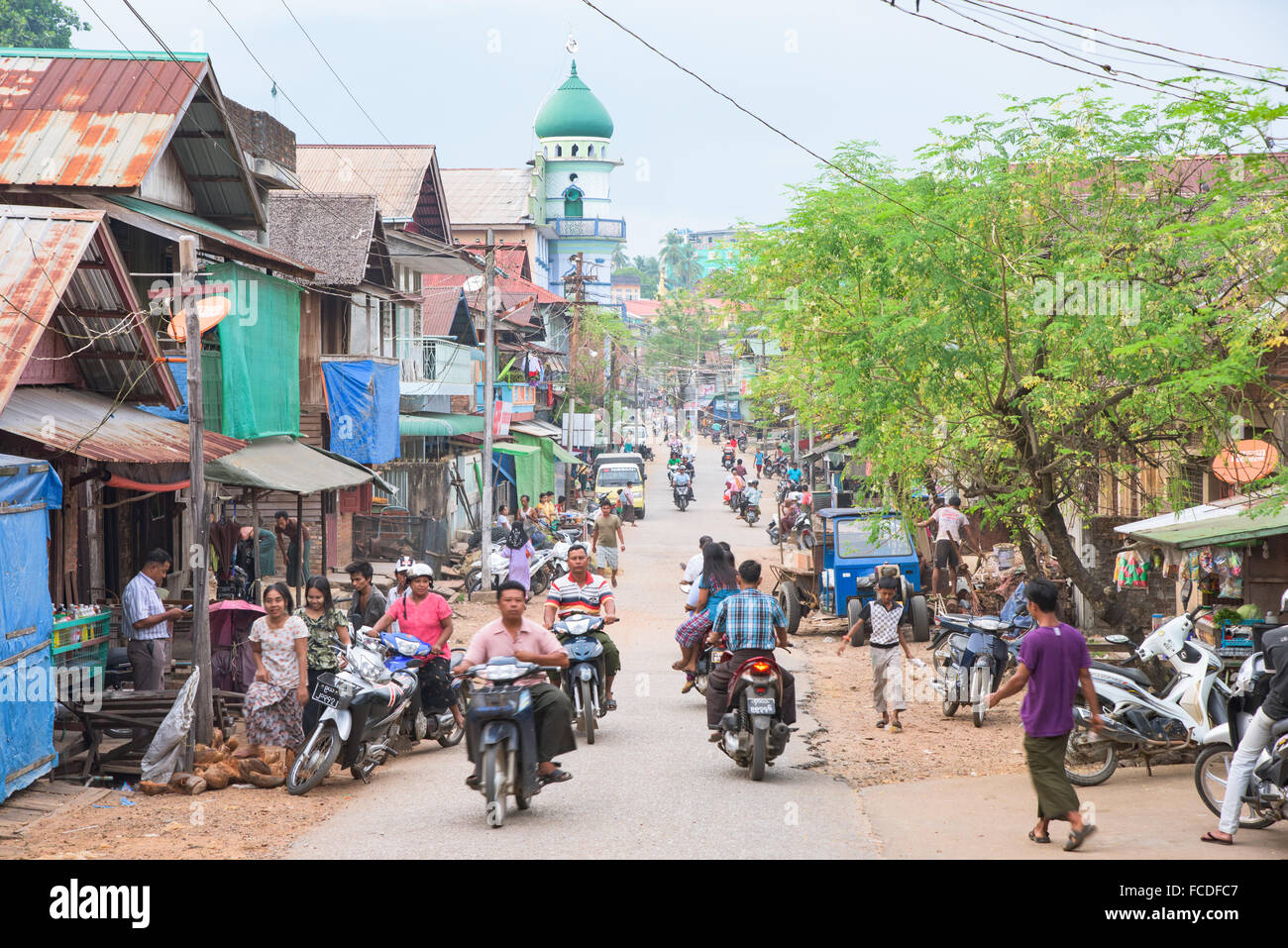 Blick auf die Straße mit einer Moschee im Hintergrund im Myeik, einer Großstadt im südlichen Myanmar. Bewegungsunschärfe auf bewegten Fahrzeugen. Stockfoto