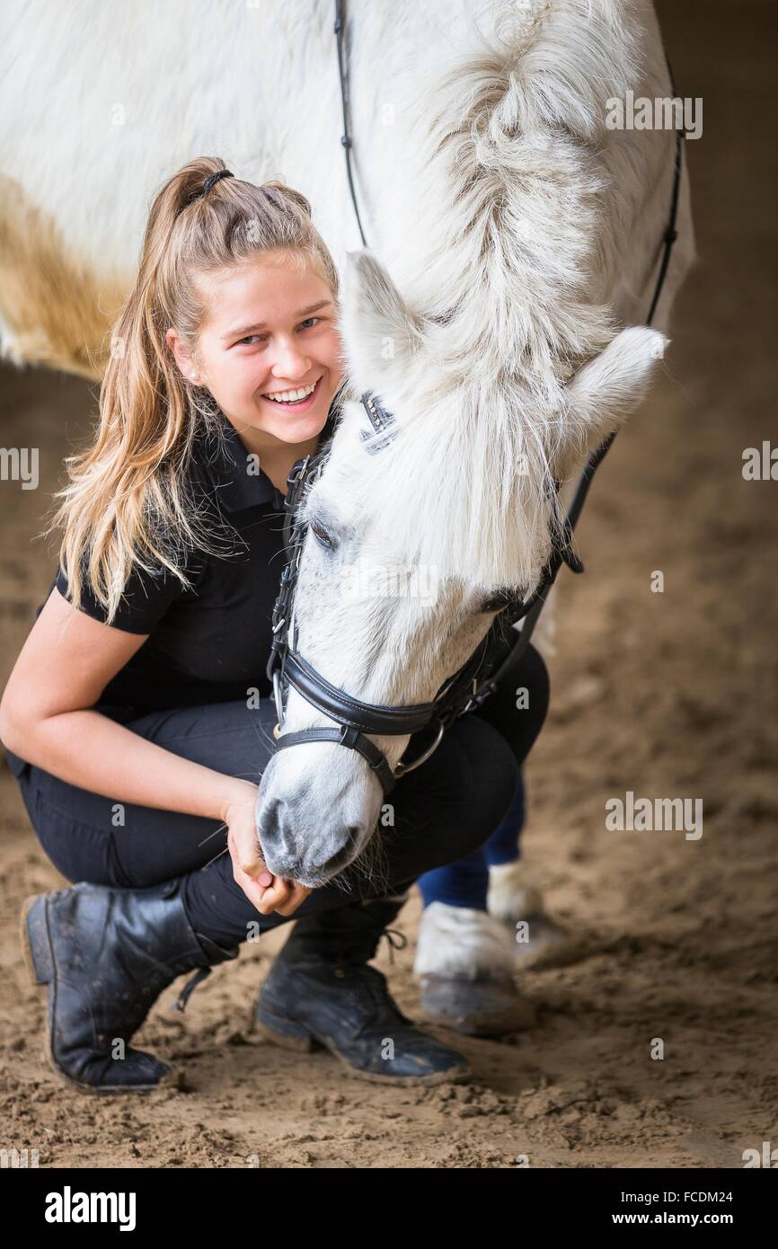Shetland-Pony. Mädchen knutschen mit einem grauen Wallach in einer Reithalle. Deutschland Stockfoto