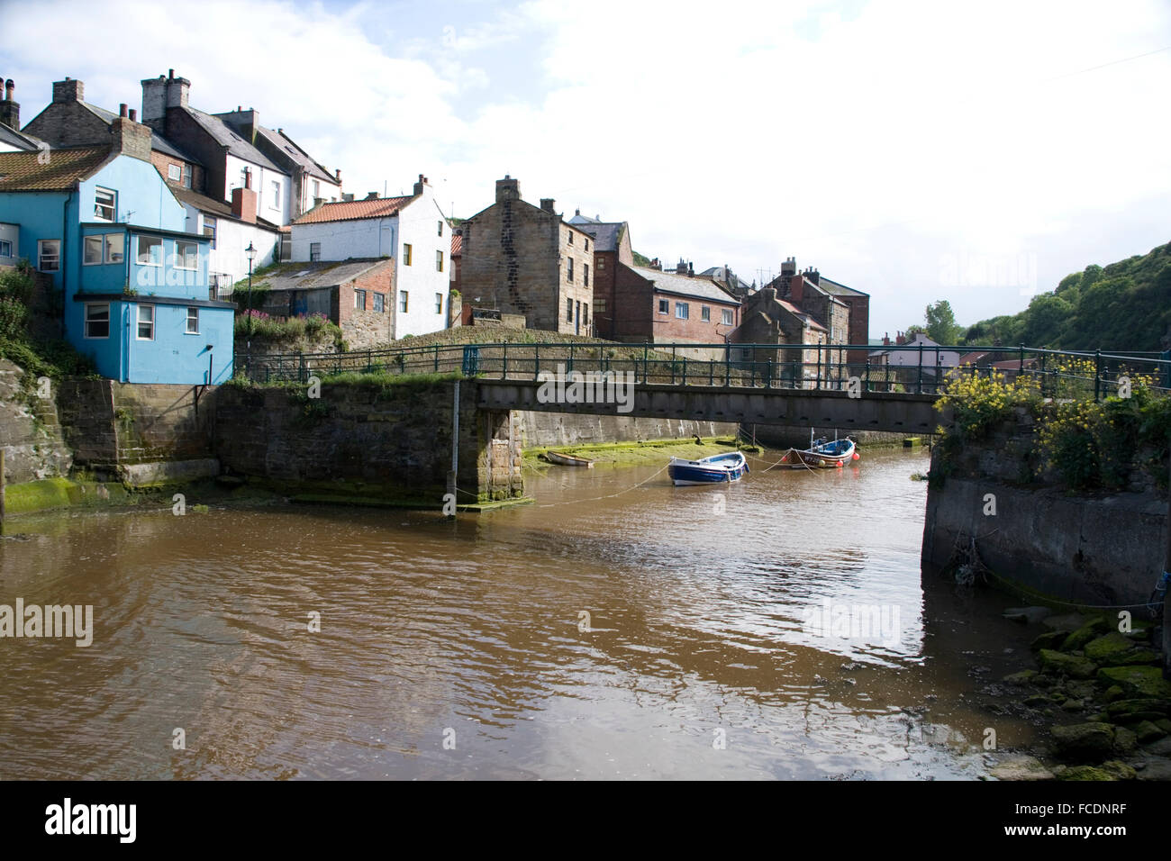 Fußgängerbrücke über den Fluss im malerischen Fischerdorf auf dem Seeweg in Staithes Yorkshire Stockfoto