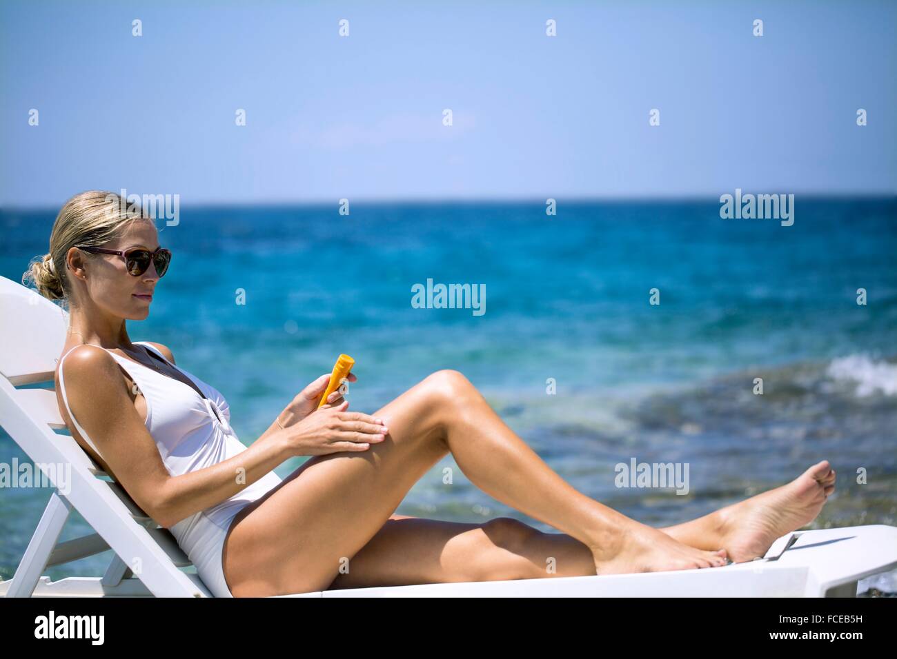 Junge Frau, die Anwendung von Sonnencreme Stockfoto