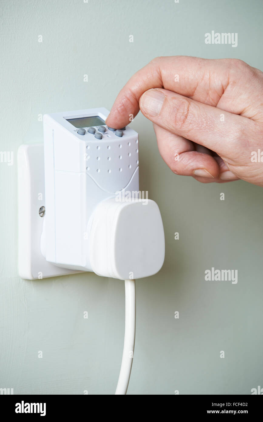 Nahaufnahme von Hand einstellen Zeitschaltuhr In Steckdose Stockfoto