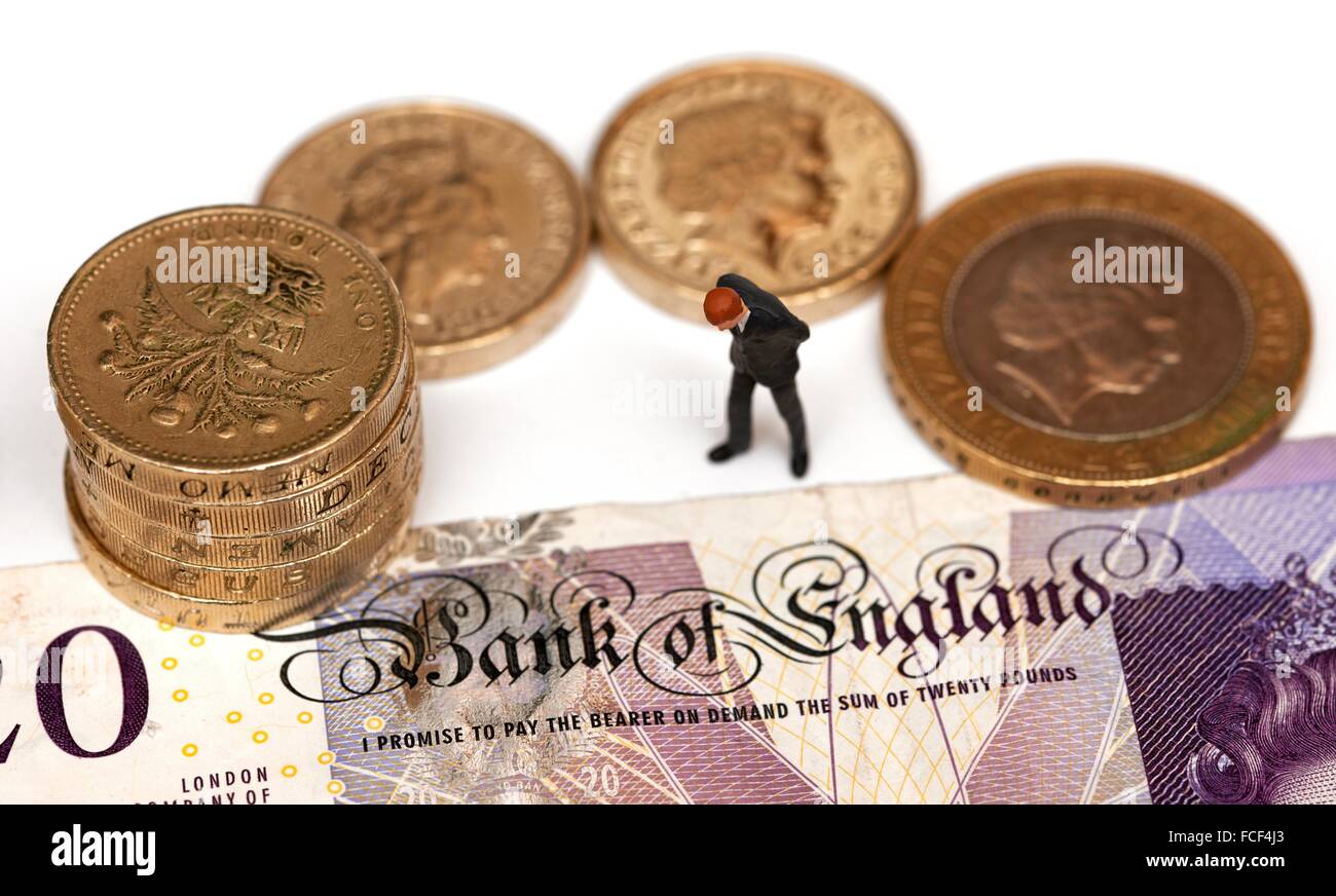 Eine Miniatur männliche Figur in einem Anzug steht neben Pfund-Münzen und einen 20-Pfund-Note zeigt die Worte Bank of England Stockfoto